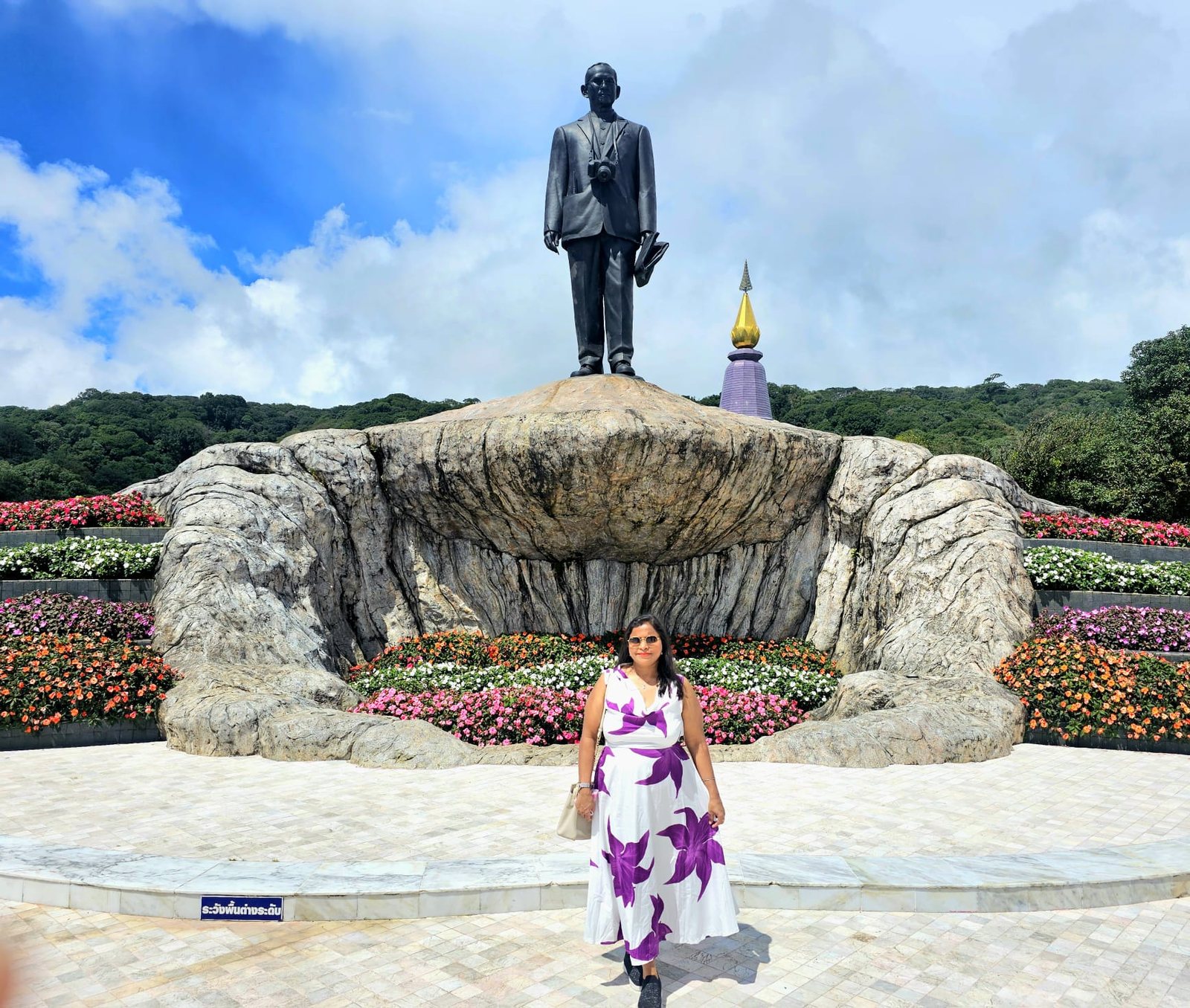 Statue on a rock plinth surrounded by flowers