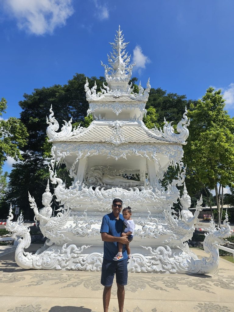 Man holding his son in front of an ornate white shrine