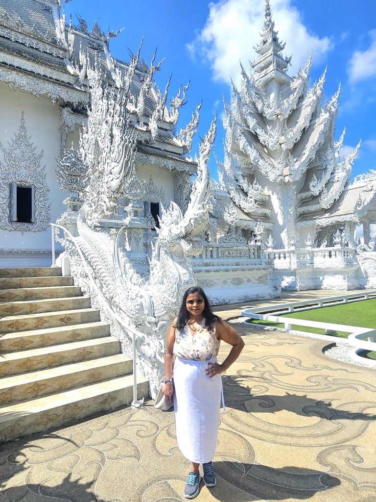Woman standing beside ornate white temple stairs
