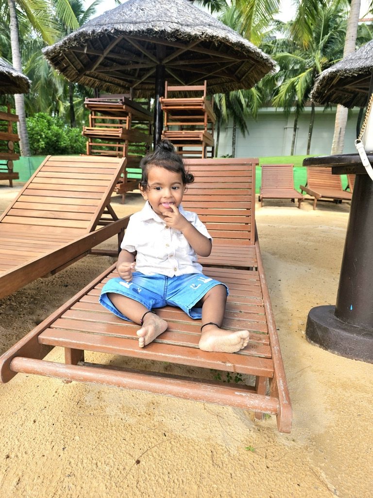 Toddler sitting on a wooden beach lounger