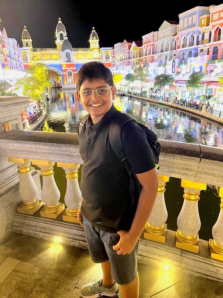 Boy standing on a balcony above a lit-up canal