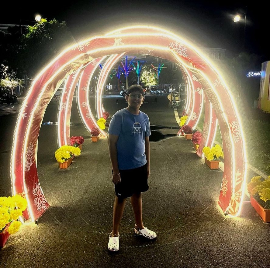 Boy standing under glowing light arches at night