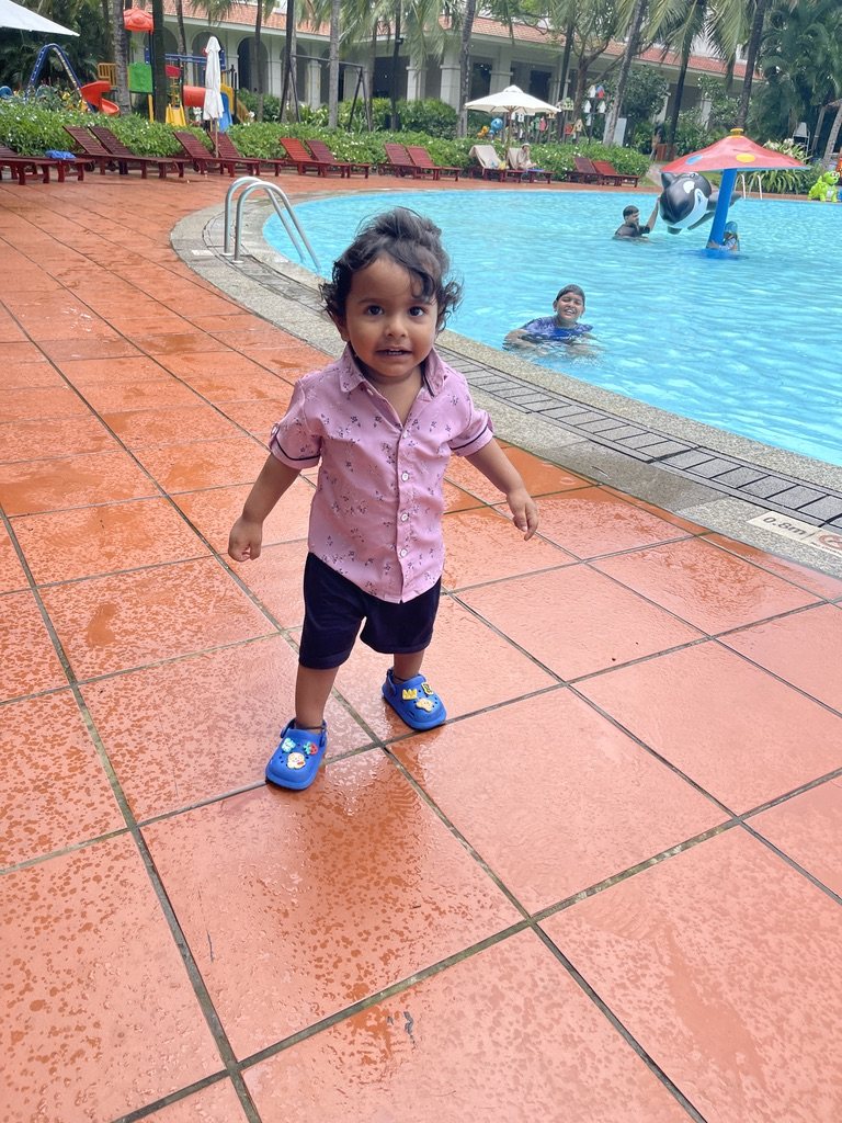Toddler walking beside a swimming pool